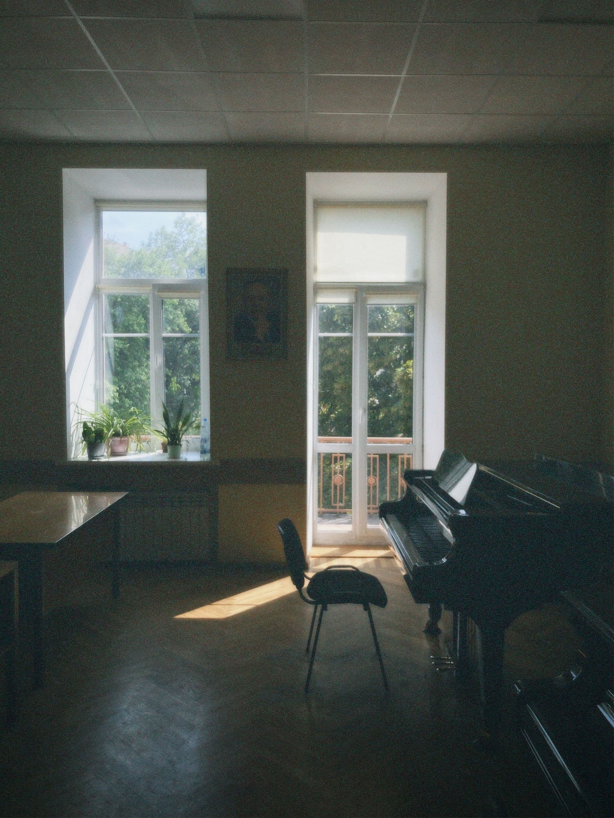 A quiet music room in daylight, with a piano and plants on the windowsill